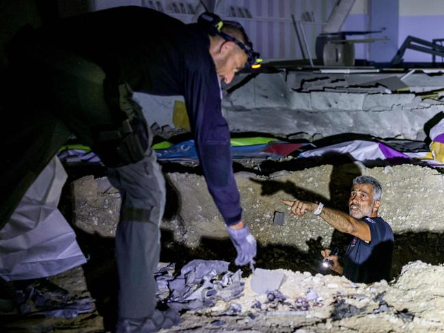 Members of Israel's Home Front Command and police forces inspect a crater left by an exploded projectile at a heavily-damaged school building in Israel's southern city of Gedera on October 1, 2024, after Iran launched a barrage of missiles at Israel in response to the killings of Lebanese Hezbollah leader Nasrallah and other Iran-backed militants. Reports said Iran fired between 150 and 200 missiles in the attack, the country's second on Israel after a missile and drone attack in April in response to a deadly Israeli air strike on the Iranian consulate in Damascus. (Photo by Menahem KAHANA / AFP)