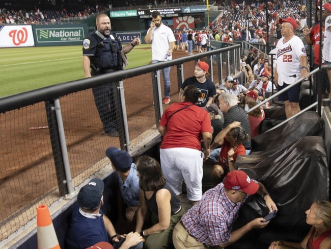 Fans take cover inside the dugout after gunfire was heard.