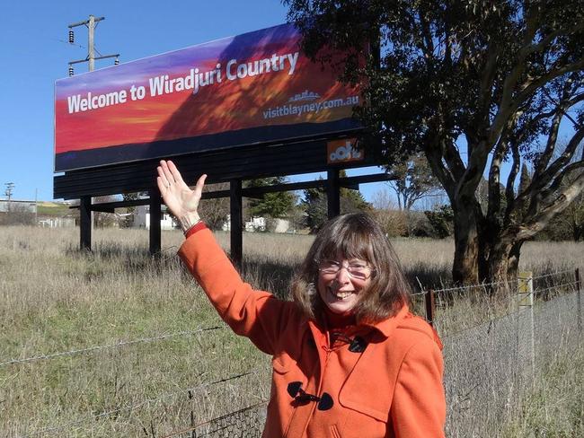 Nyree Reynolds poses in front of a billboard showing her  artwork that had been transferred onto Wiradjuri Ngurambang (country) signs, taken  on the Mid Western Highway between Cowra and Lyndhurst in 2016. Picture: Facebook / Wiradjuri Mob