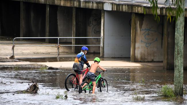 Two boys play in receding floodwaters under the new Doug Ladner Bridge, which played its critical role in keeping the north and south of Ingham linked during the disaster. The floods in Hinchinbrook Shire, North Queensland. Picture: Cameron Bates