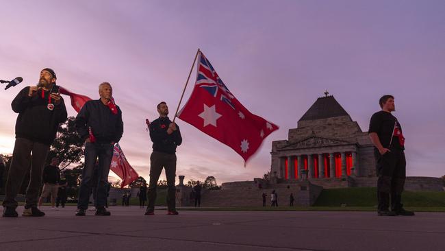 People holding the Australian Red Ensign pay their respects during the Anzac Day Dawn Service at the Shrine of Remembrance in Melbourne.