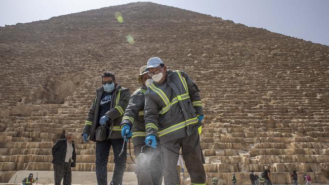 Municipal workers sanitise the walkways around the Giza pyramid complex . Picture: AP.