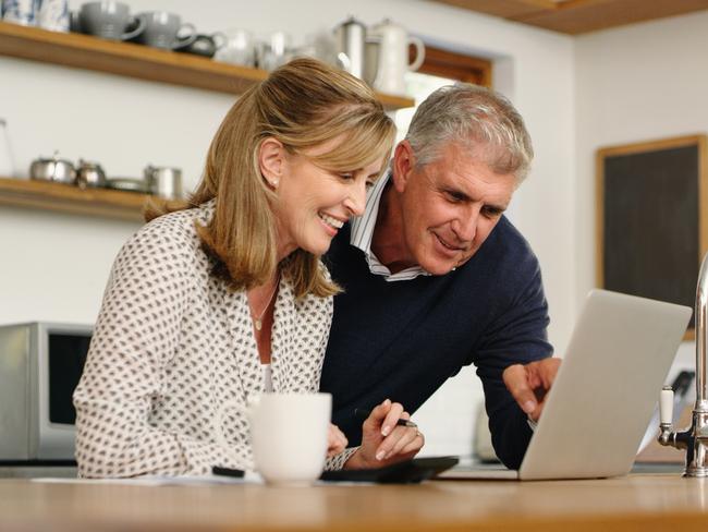 A senior couple planning their finance and paying bills while using a laptop at home. A mature man and woman going through paperwork and working online with a computer; superannuation money generic