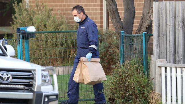 A forensic officer removes bags of evidence from the scene. Picture: David Crosling