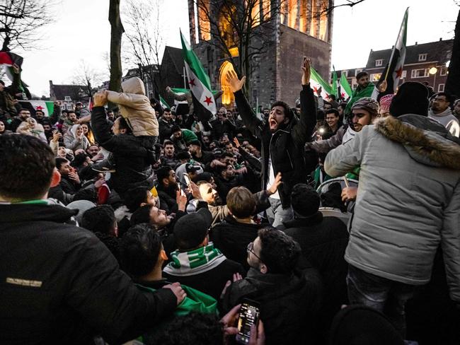 Crowds wave Syrian opposition flags to celebrate the fall of long-time ruler Bashar al-Assad. Picture: AFP