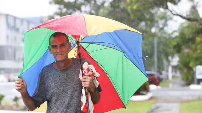 Michael Evans uses an old umbrella to shelter from the rain in the windy and wet weather. A tropical low in the Coral Sea is forecast to develop into a cyclone in the coming days. Picture: Brendan Radke