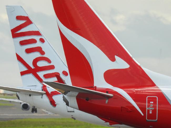 The vertical stabilisers of a Qantas Boeing B737-838 plane, registration VH-VZQ, and a Virgin Australia Boeing B737-8FE plane, registration VH-VUZ, waiting at the northern end of the main runway of Sydney Kingsford-Smith Airport in preparation for departure.  The Qantas plane is heading to Adelaide as flight QF741 and the Virgin plane is heading to Adelaide as flight VA428.  In the background is another Virgin B737-8FE plane. This image was taken from Nigel Love Bridge, Mascot on a sunny afternoon on 3 December 2023.Escape 9 February 2025Cover storyPhoto - iStock