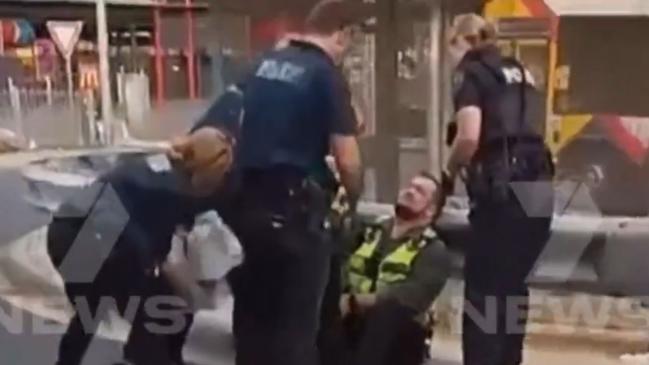 Police assist the security guard after he was stabbed at work. Picture: 7NEWS