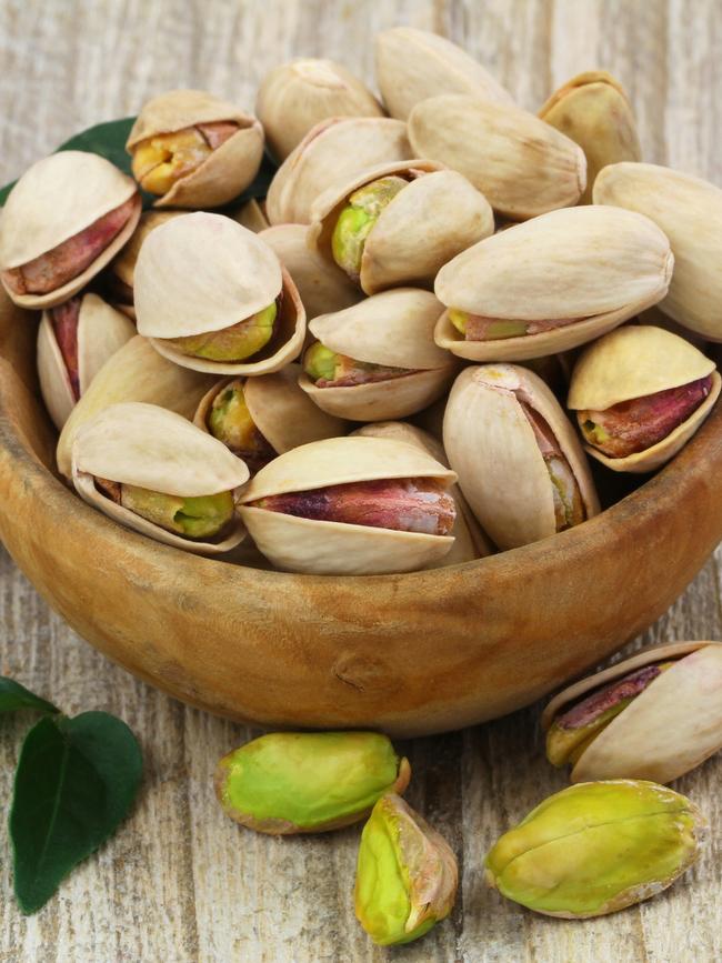 Pistachios with and without shell in wooden bowl with copy space