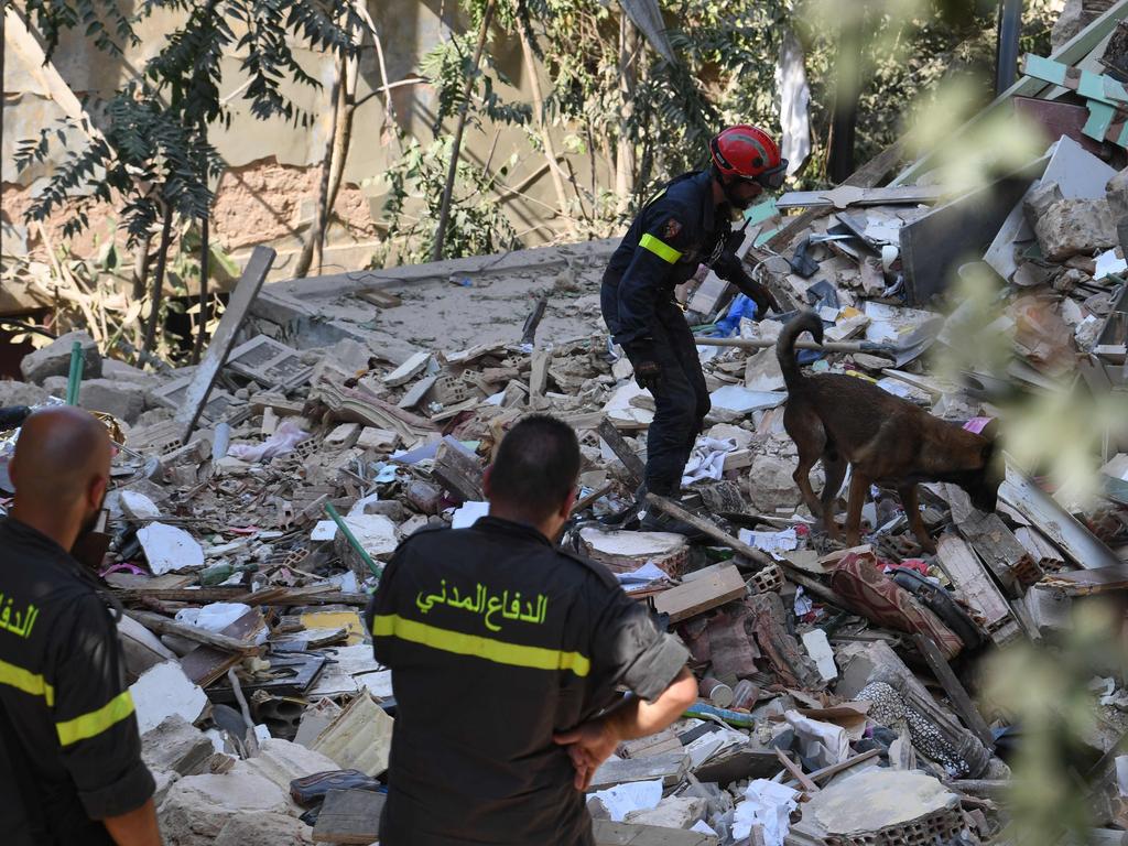 Members of the Lebanese civil defence look on as French rescuers use a dog to search for victims and survivors amid the rubble. Picture: AFP