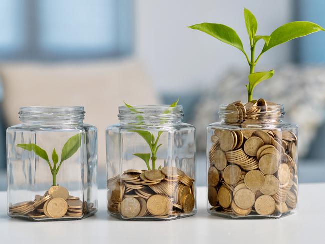 Green plant growing in glass jar with coins, superannuation generic