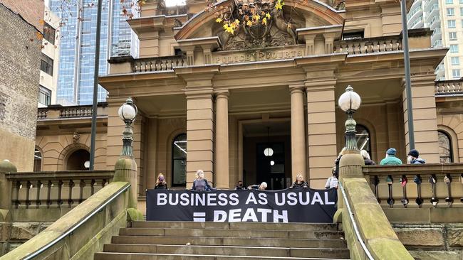 Blockade Australia supporters outside Central Local Court on June 27 with a banner: "Business as usual = death". Picture: NewsLocal