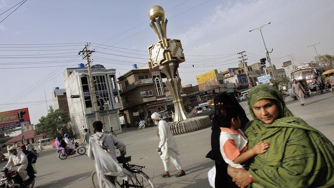 A giant gold-coloured football statue stands at the centre of a major intersection in Sialkot.