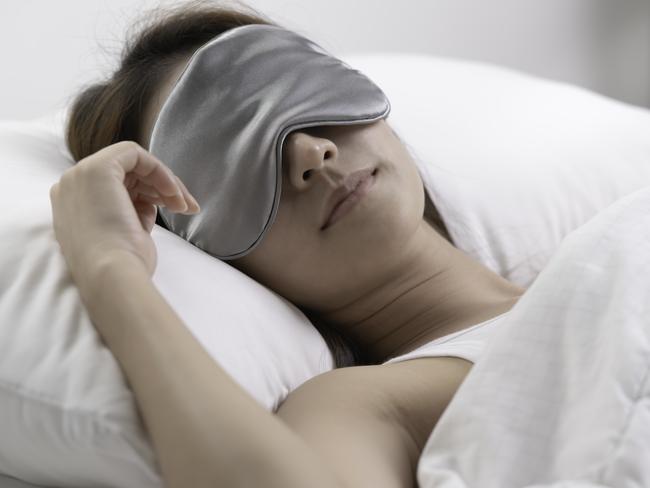 Young woman with eye mask sleeping in her bed and relaxing in the morning