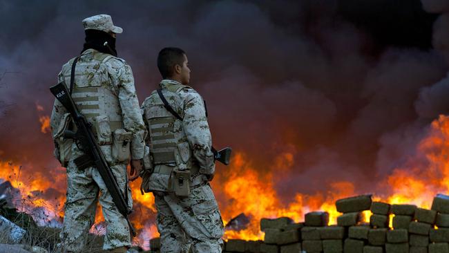 Two soldiers watch 134 tonnes of marijuana burning in the border town of Tijuana, Mexico, seized by the Mexican Army after a clash with drug traffickers in October 2010. Picture: AFP Photo/Francisco Vega