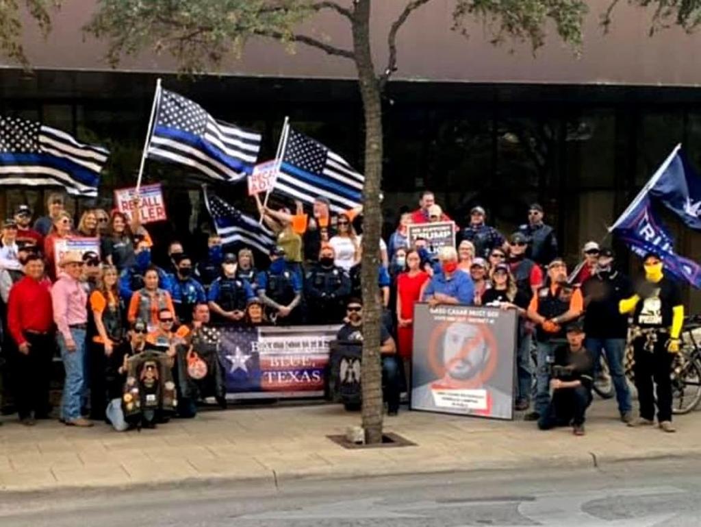 A photo featuring members of the Austin Police Department at a pro-police rally. On the far-right of the photo a Proud Boys member flashed a sign associated with white supremacy.