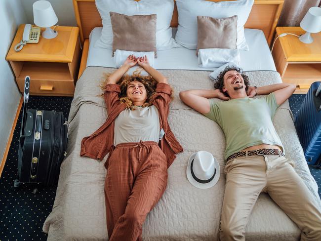 Young cheerful couple lying on the bed after arriving at their hotel room