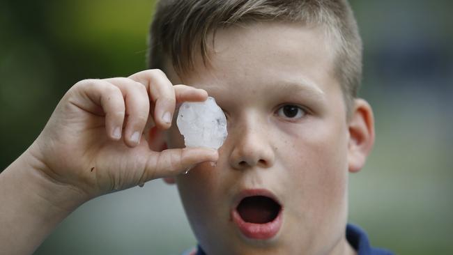 Cooper 10, holds one of the large hail stones that pelted down. Picture: David Caird