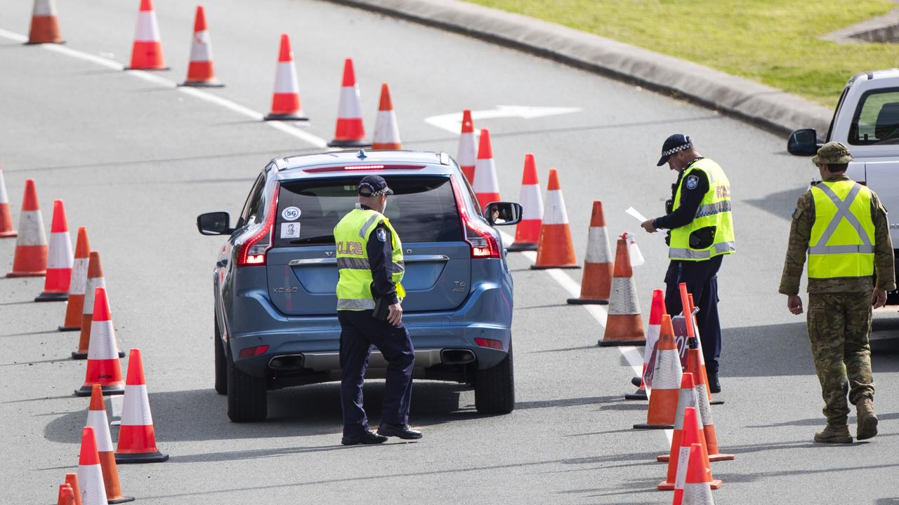 Police and ADF officials check cars at the Queensland border. Picture: Nigel Hallett