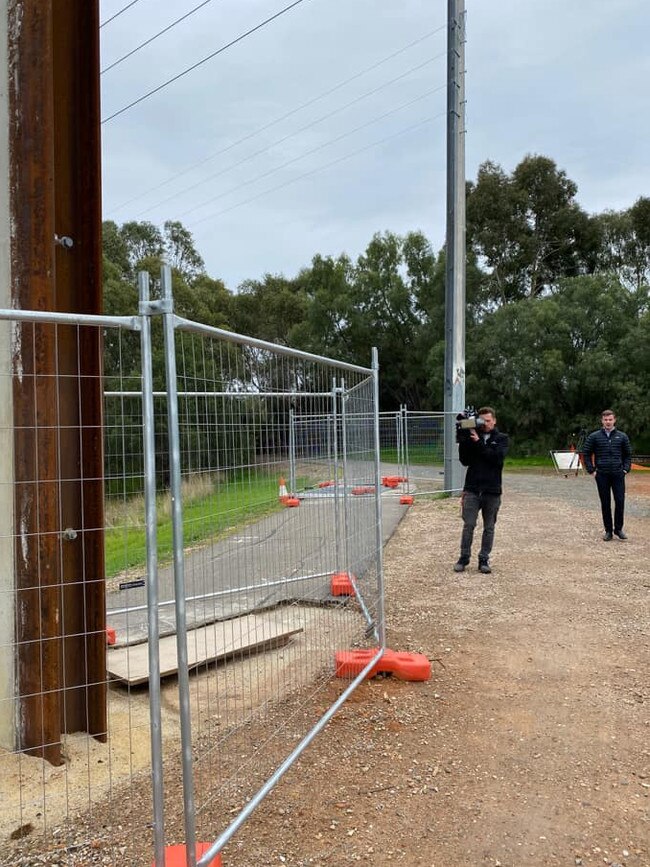 A 7NEWS crew films the bizarrely placed Stobie pole, with the second one visible behind them.