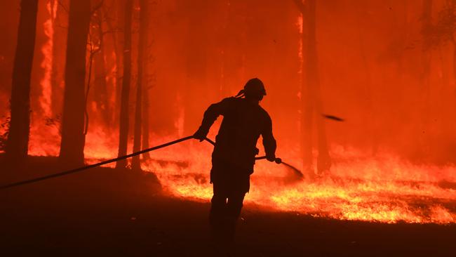 RFS volunteers and NSW Fire and Rescue officers protect a home impacted by the relentless Gospers Mountain fire near Colo Heights on November 19. (AAP Image/Dean Lewins)