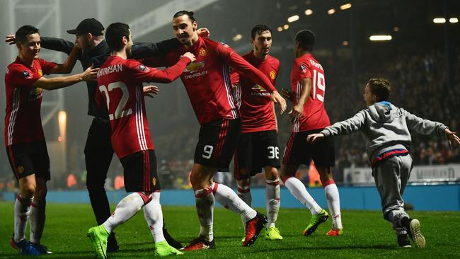 A young fan runs onto the pitch as Zlatan Ibrahimovic of Manchester United (9) celebrates with team mates as he scores.