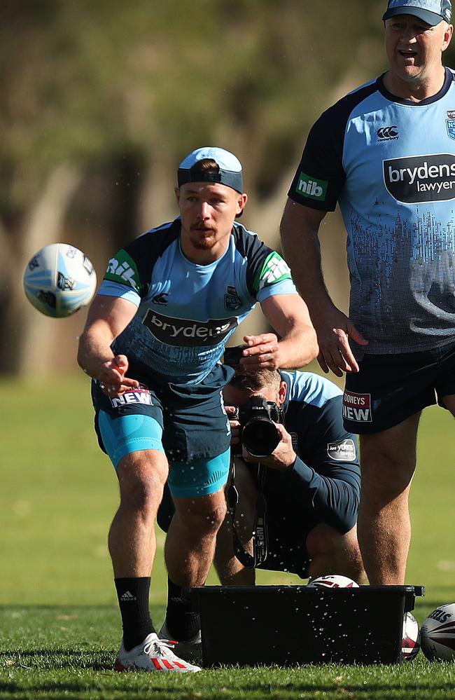 Damien Cook passes wet balls from a tub of water at training. Picture: Brett Costello