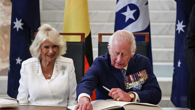 Queen Camilla and King Charles sign the visitor’s book at Parliament House on Monday. Picture: NewsWire/David Gray