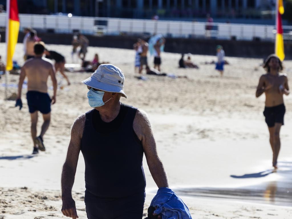 A man wearing a mask walks along Bondi Beach as restrictions eased further across NSW. From today, masks are only required on public transport and in airports, or for indoor front-of-house hospitality staff. Picture: Jenny Evans/Getty Images