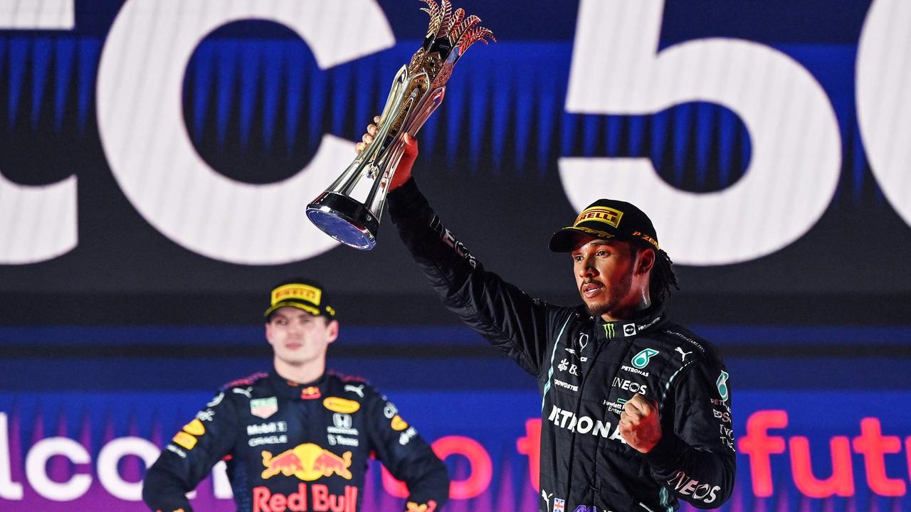 TOPSHOT - Winner Mercedes' British driver Lewis Hamilton (R) reacts with his trophy flanked by second-placed Red Bull's Dutch driver Max Verstappen (L) during the podium ceremony after the Formula One Saudi Arabian Grand Prix at the Jeddah Corniche Circuit in Jeddah on December 5, 2021. (Photo by ANDREJ ISAKOVIC / POOL / AFP)
