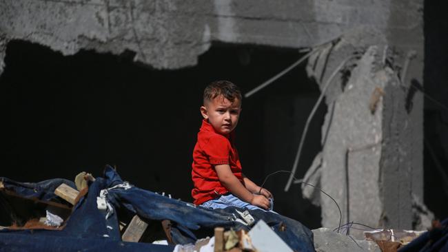 A Palestinian boy sits on the rubble as people search for a family following Israeli strikes in al-Bureij refugee camp. Picture: AFP