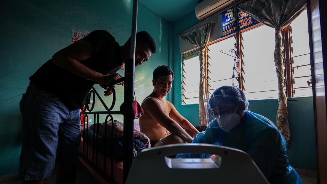 A medical heath worker (right) provides consultation and instruction to Andrew Ro (centre) and his housemate (left) during a door-to-door medical visitation. After a year marred by arrests and outbursts of anti-foreigner rhetoric, migrants and refugees are wary to seek Malaysia's government healthcare services in fear of they will be arrested or detained. Picture: Annice Lyn/Getty Images