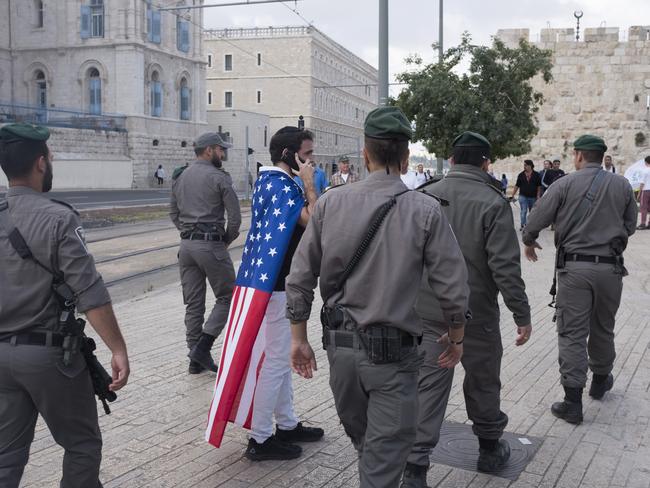 Israeli border policemen walk next to a man wearing an American flag outside the Old City in Jerusalem. Picture: Getty