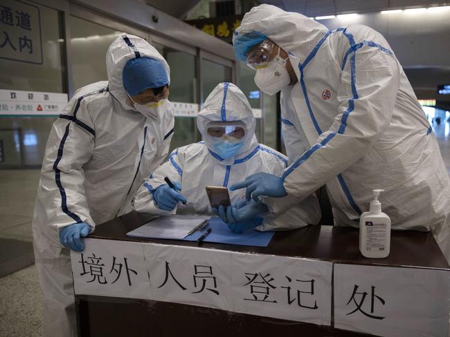 Health workers check details of a passenger arriving from Beijing at the train station in Wuhan in central China's Hubei. Picture: AP