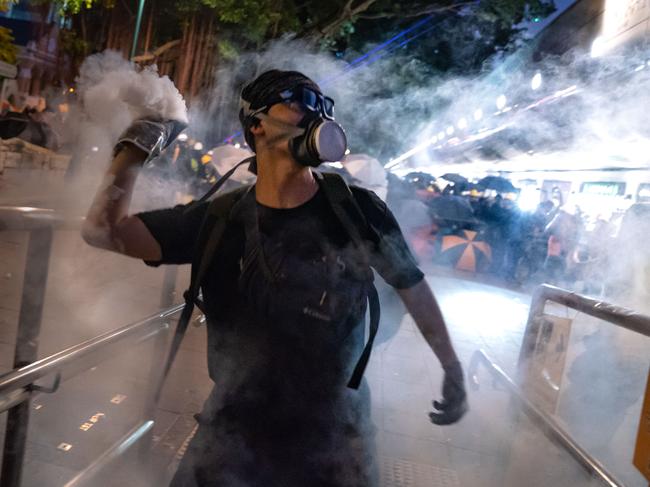 A protester throws back tear gas fired by riot police in the Cheung Sha Wan area. Picture: Getty