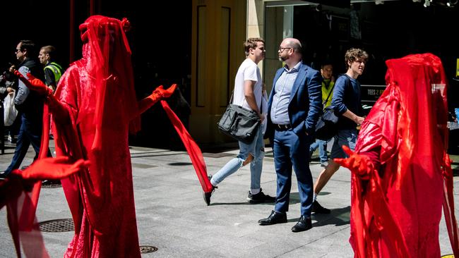 A man in a suit watches ‘red rebel’ protesters dressed in red during the Extinction Rebellion 'Die-In' in Adelaide this week. Picture: Morgan Sette/AAP