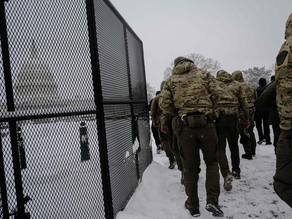 Members of law enforcement enter the secure fencing surrounding the US Capitol during a snow storm on January 6. Picture: Jon Cherry/Getty Images/AFP