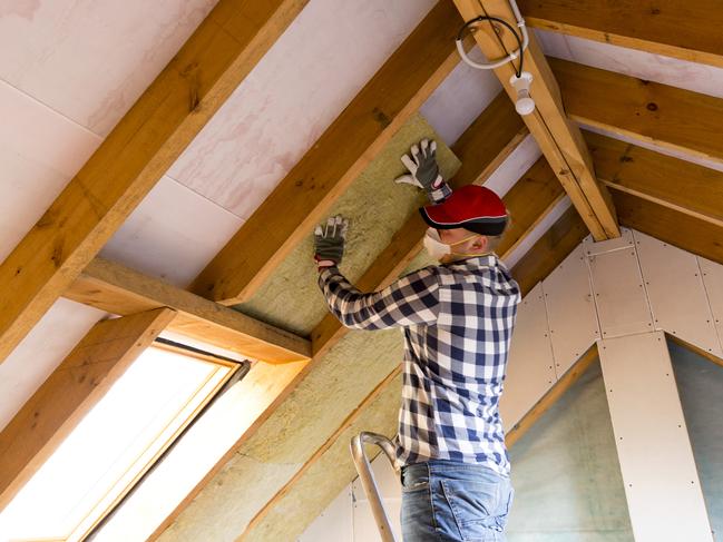 Man installing thermal roof insulation layer - using mineral wool panels. Attic renovation and insulation concept