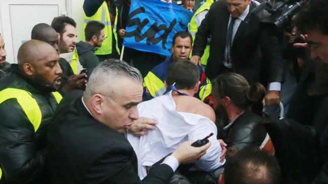 Air France director of Human Ressources, Xavier Broseta, center (back to the camera), protected by security guards tries to flee the Air France headquarters at Roissy Airport, north of Paris, France, during scuffles with union activists, Monday, Oct. 5, 2015. Union activists protesting proposed layoffs at Air France stormed the headquarters during a meeting about the job cuts, zeroing in on two managers who had their shirts torn from their bodies, scaled a fence and fled under police protection. (AP Photo/Jacques Brinon)