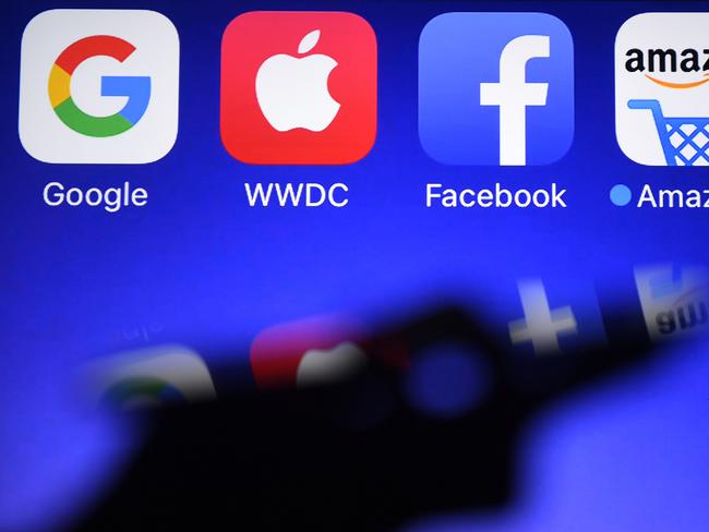 (FILES) In this file photograph taken on September 28, 2017, shows a smartphone being operated in front of GAFA logos (acronym for Google, Apple, Facebook and Amazon web giants) as background in HÃ©dÃ©-Bazouges, western France. - Big Tech, its hands full with antitrust probes and complaints growing from activists and politicians, turns its attention to quarterly earnings in the coming days expected to show the growing power of Silicon Valley giants. (Photo by Damien MEYER / AFP)