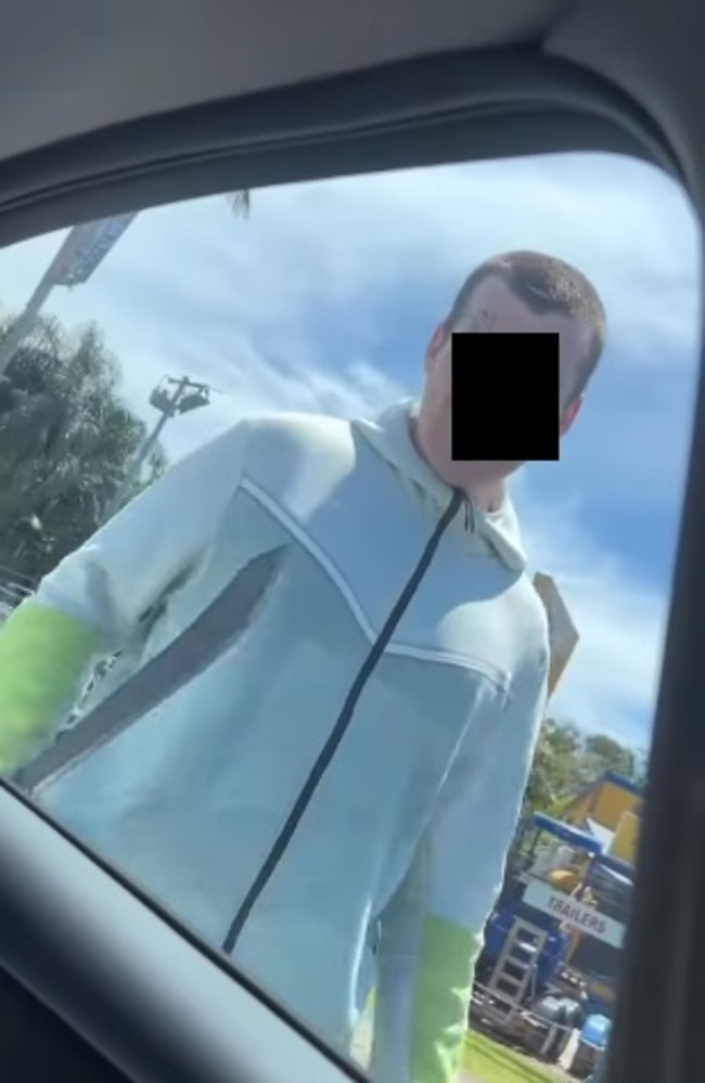 A man with a machete taps on a car window
