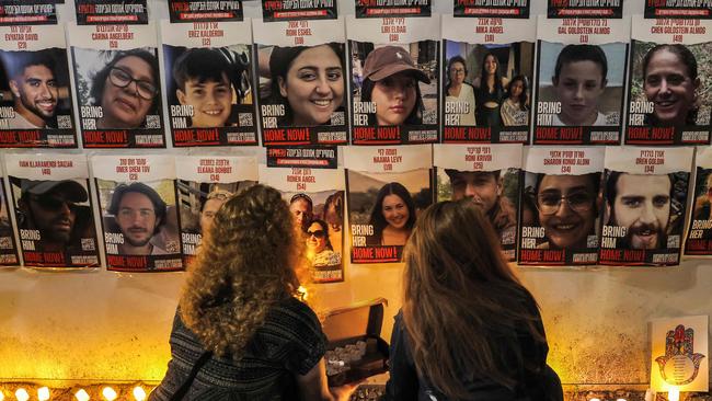 People light candles beneath a wall showing posters identifying hostages at a vigil demanding government action for their return outside the Israeli parliament in Jerusalem. Picture: AFP