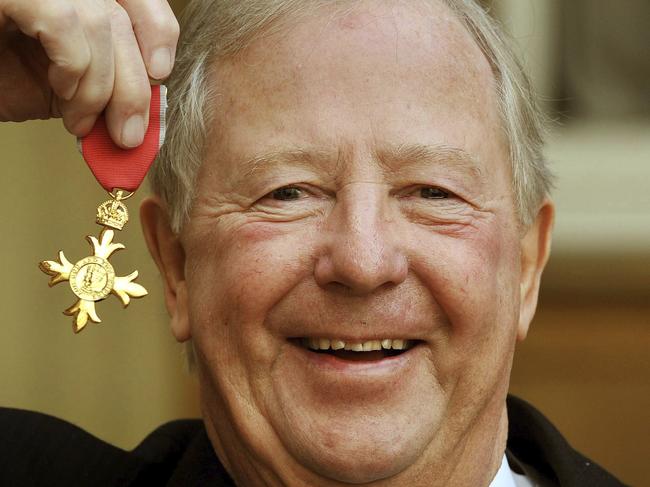 FILE - In this Nov. 28, 2011 file photo, Tim Brooke-Taylor holds his OBE after being presented it by Queen Elizabeth, outside Buckingham Palace in London.  British comedian Tim Brooke-Taylor, a member of comedy trio The Goodies, has died after contracting the new coronavirus. He was 79. Brooke-Taylorâ€™s agent says he died Sunday, April 12, 2020 â€œfrom COVID-19.â€(John Stillwell/PA via AP)