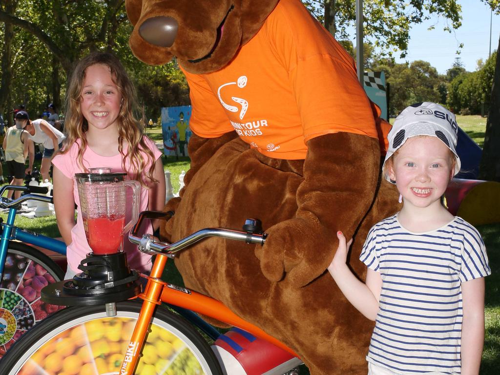 Lucy Nesbitt, 5, and sister Estelle, 9, help Mascot 'Oppy' The Kangaroo, make cooling watermelon juice drinks at the Santos TDU, Stage 4 Adelaide Street Circuit, on Sunday, January 13. Picture: AAP/Emma Brasier