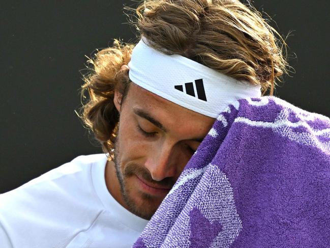 Greece's Stefanos Tsitsipas uses a towel during a break in play against Finland's Emil Ruusuvuori during their men's second round singles tennis match on the fourth day of the 2024 Wimbledon Championships at The All England Lawn Tennis and Croquet Club in Wimbledon, southwest London, on July 4, 2024. (Photo by ANDREJ ISAKOVIC / AFP) / RESTRICTED TO EDITORIAL USE