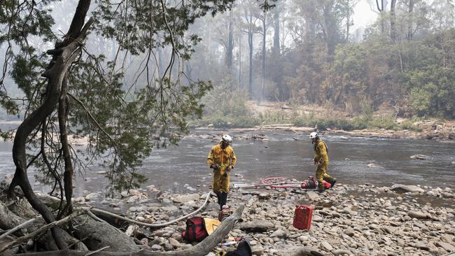 TFS Rats Michael Marshall and Luke Mellers pump water from the Huon River below the branches of Huon Pine. Picture: WARREN FREY/TFS