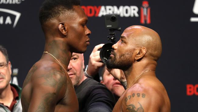 UFC middleweight champion Israel Adesanya, front left, of Nigeria, and challenger Yoel Romero, right, of Cuba, face off during a ceremonial weigh-in for UFC 248 at T-Mobile Arena in Las Vegas, Friday, March 6, 2020. UFC president Dana White keeps the fighters separated. Adesanya will defend his title against Romero at the arena on Saturday, March 7. (Steve Marcus/Las Vegas Sun via AP)