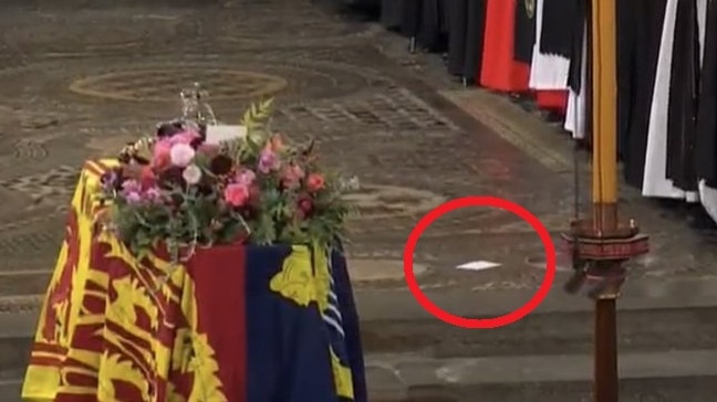 The errant piece of paper beside the Queen's coffin.