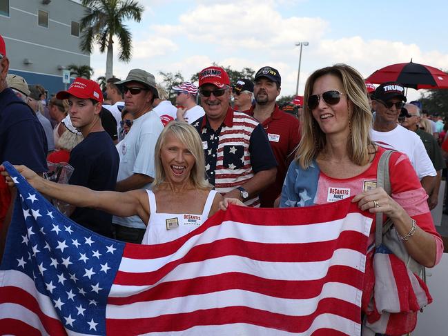 ESTERO, FL - OCTOBER 31: Two women hold an American flag as people stand in line for President Donald Trump's campaign rally at the Hertz Arena on October 31, 2018 in Estero, Florida. President Trump continues travelling across America to help get the vote out for Republican candidates ahead of the midterm elections.   Joe Raedle/Getty Images/AFP == FOR NEWSPAPERS, INTERNET, TELCOS & TELEVISION USE ONLY ==