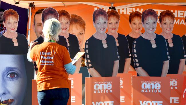 A One Nation volunteer adjusts cardboard cutouts of One Nation leader Pauline Hanson at a pre-polling station near Brisbane. Picture: AAP Image/Mick Tsikas